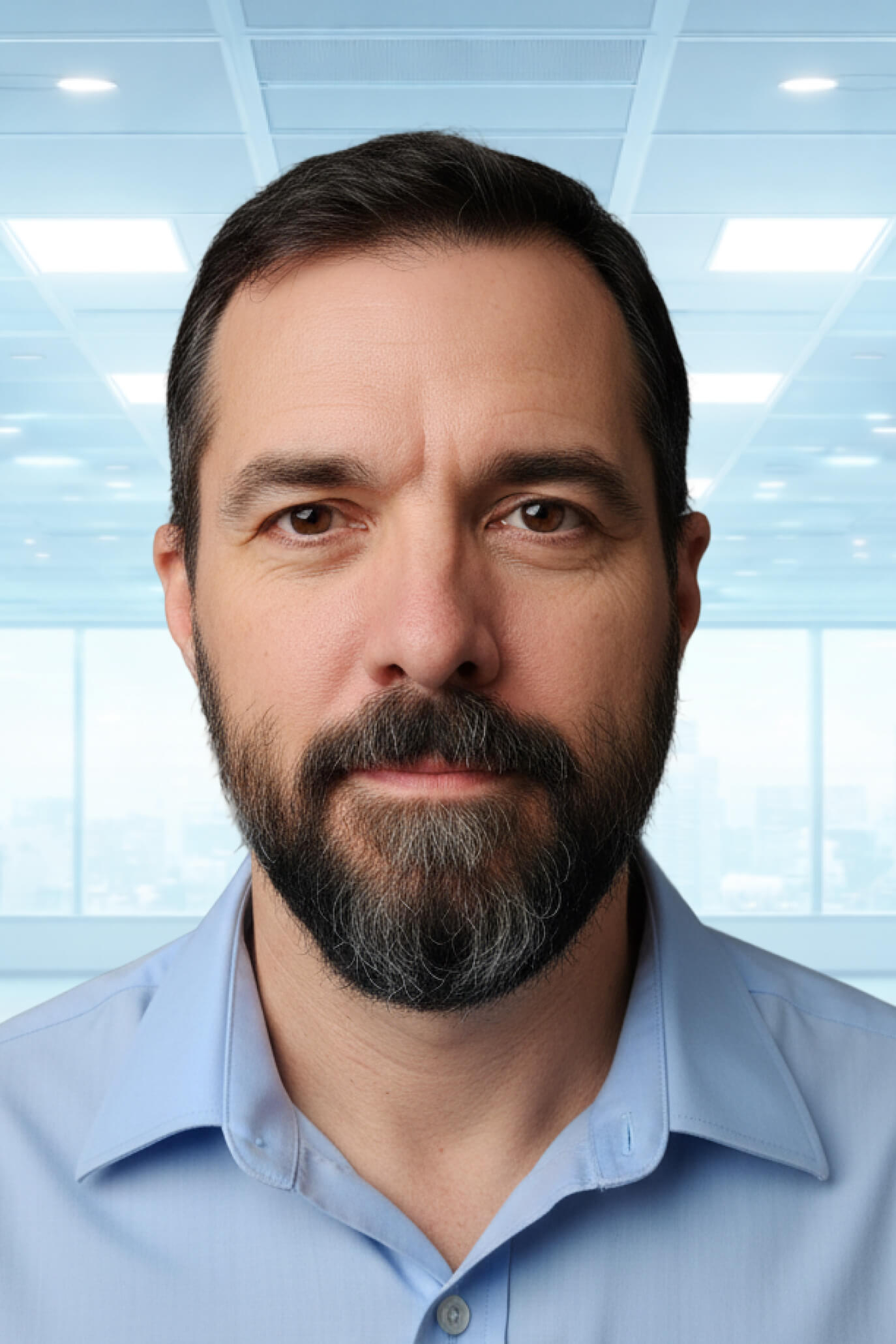Professional headshot of Jason Shiffer, a bearded man in a light blue dress shirt, in a modern office setting.